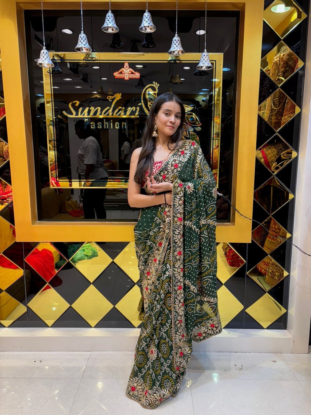 Woman in a floral dress standing in front of a store with 'Sundari Fashion' sign.
