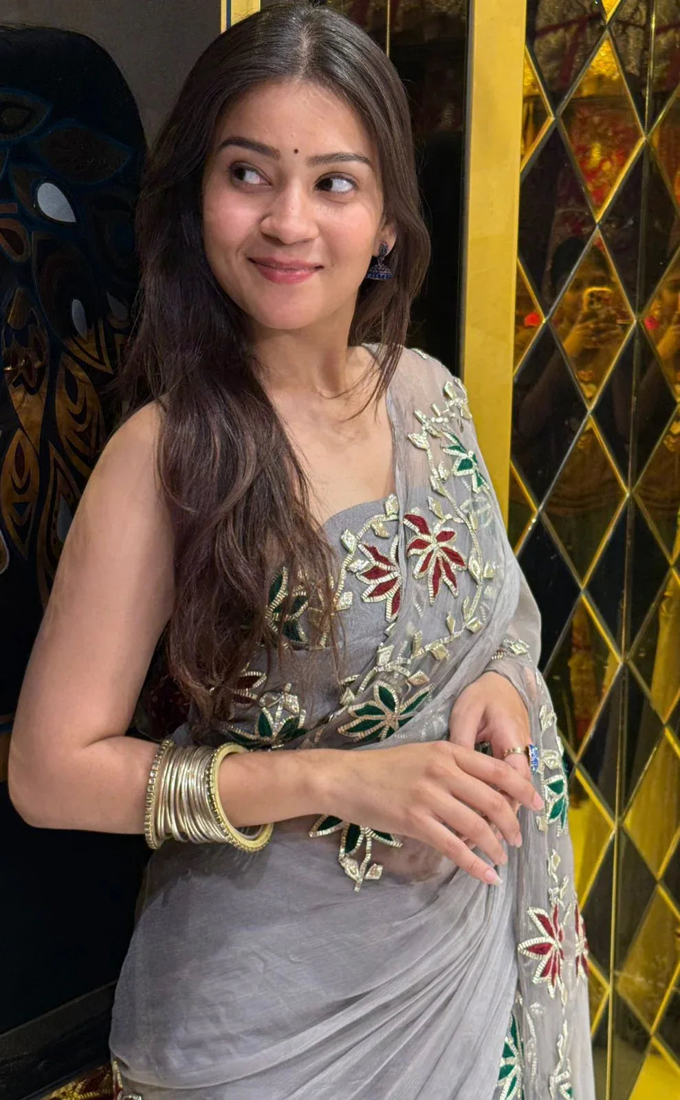 Woman in a traditional embroidered saree with a decorative background