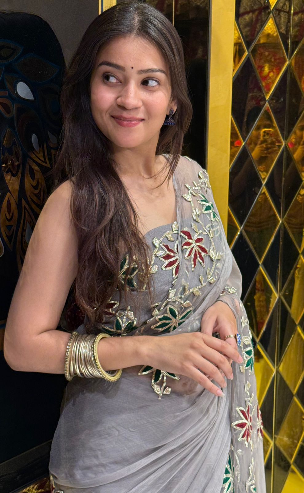 Woman in a traditional embroidered saree with a decorative background